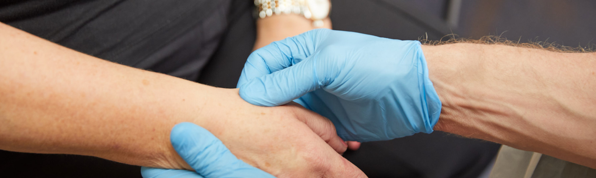 A photo showing a clinician checking a patients pulse