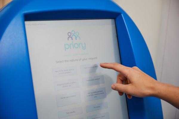 A photo showing a patient using the prioryCARE form on the computer based in reception