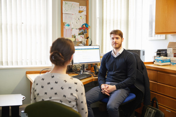 A photo showing a pharmacist speaking to a patient