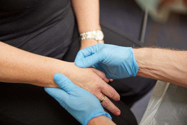A photo showing a clinician checking a patients pulse